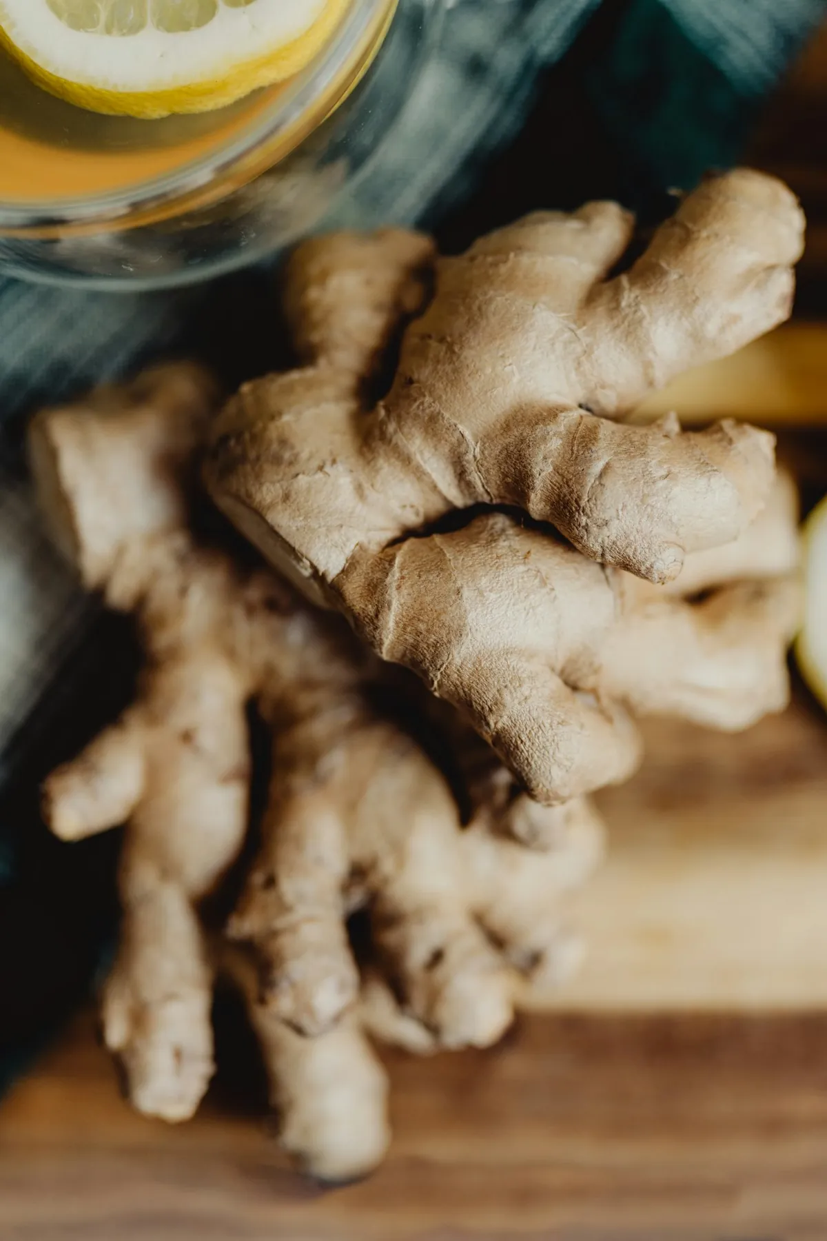 Fresh ginger root and lemon beside a glass of juice