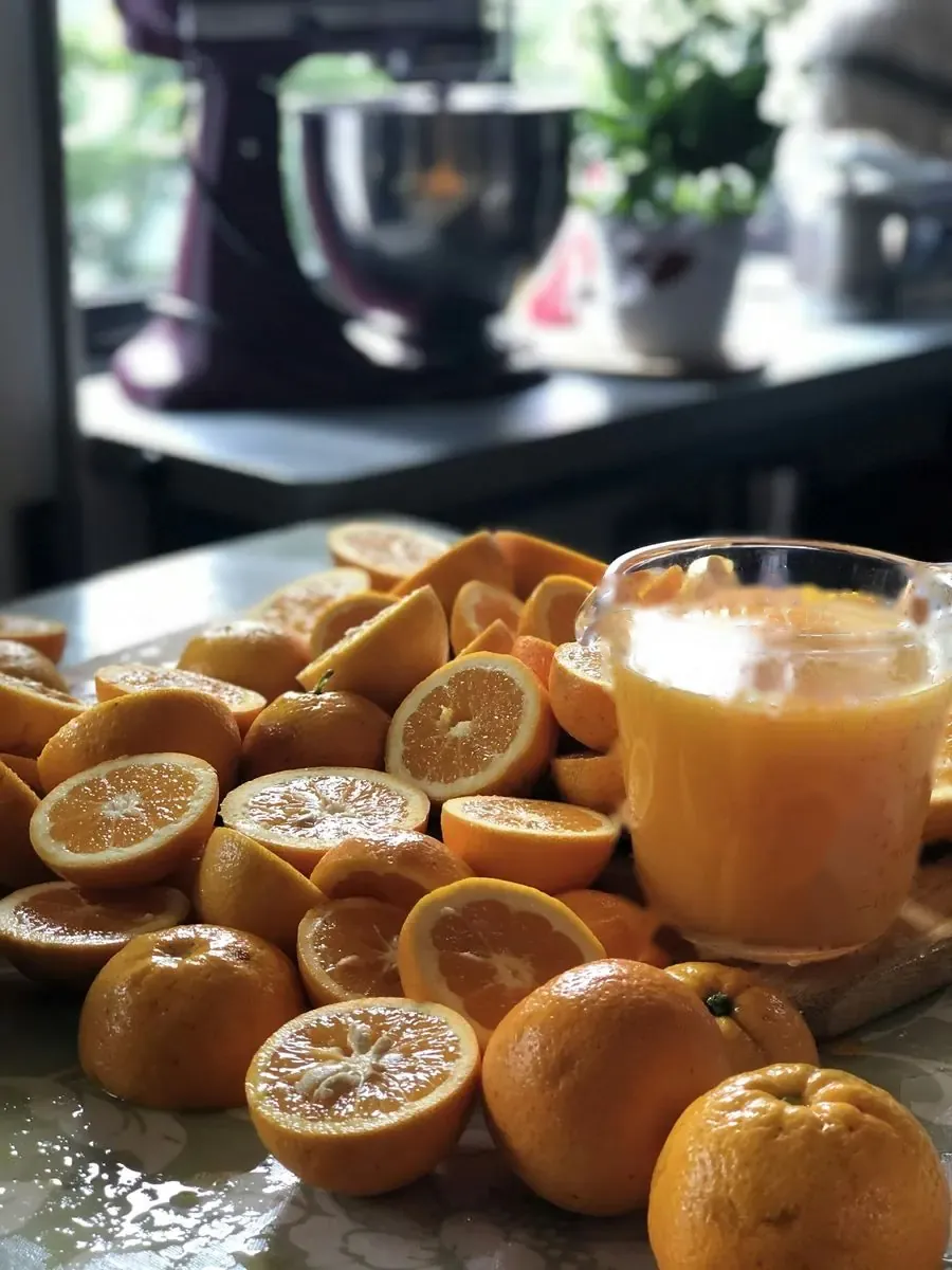 Freshly cut orange halves next to a jug of just-pressed juice