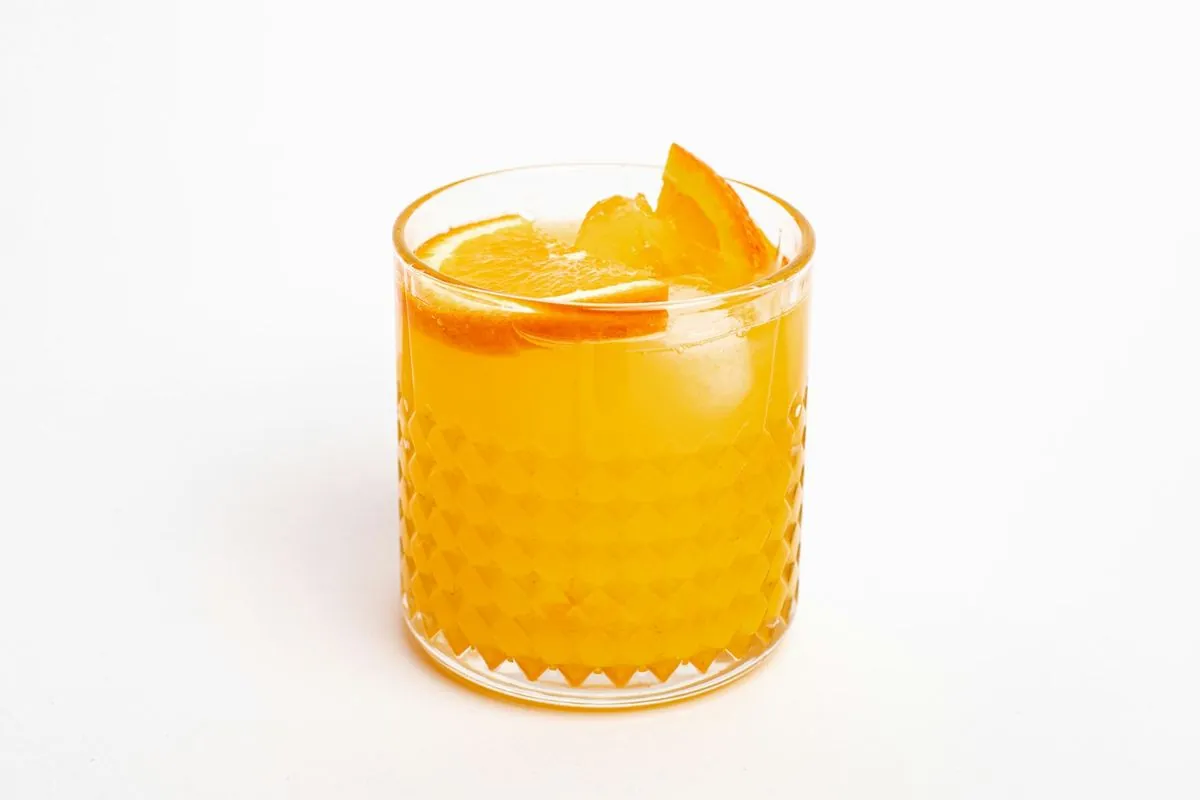 A glass of orange juice with a slice on the rim